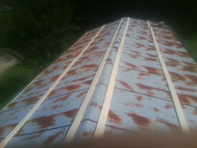 Rusted metal roof panels with new wood purlins before replacement — Storm Damage Roof Repair in Henrietta by Roofing Brothers