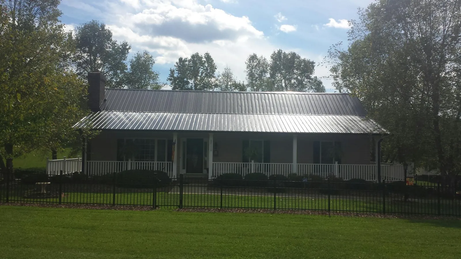 Gray metal roof on a brick ranch with a full width front porch — Gutter Guard Installation work by our crew in Henrietta